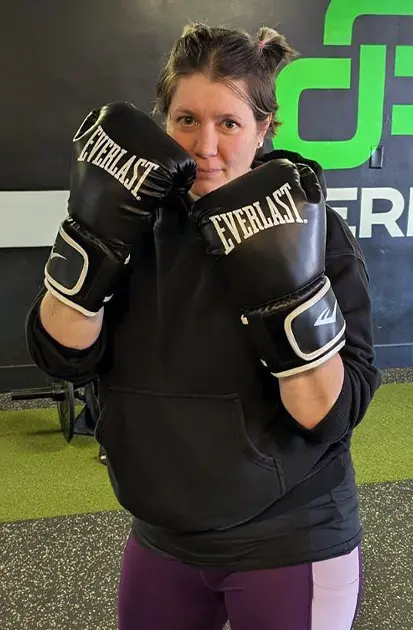 Woman in a boxing stance wearing gloves during a gym boxing workout