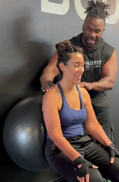 Coach guiding a member through a seated stability ball exercise during personal training